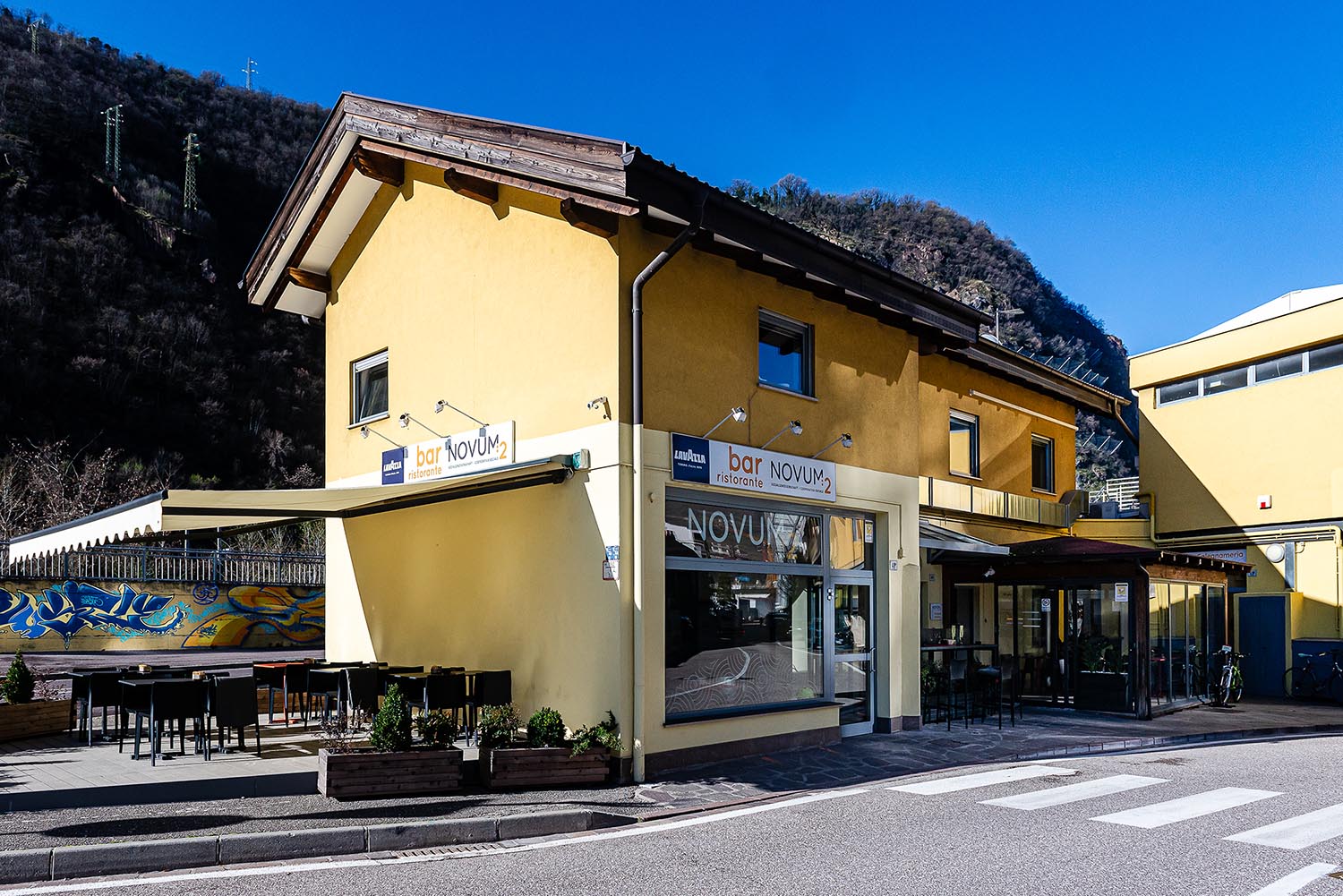 Vista esterna del Bar Novum2 con tenda da sole e tavoli esterni